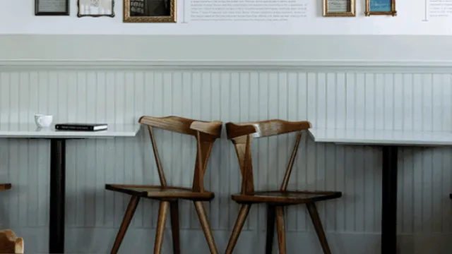 A chic wall display titled &ldquo;Sylvia Beach&rdquo; with photos, captions, and frames arranged chronologically, plus a plant and wooden stools beneath. Top it at 140 characters, always ending the sentence.